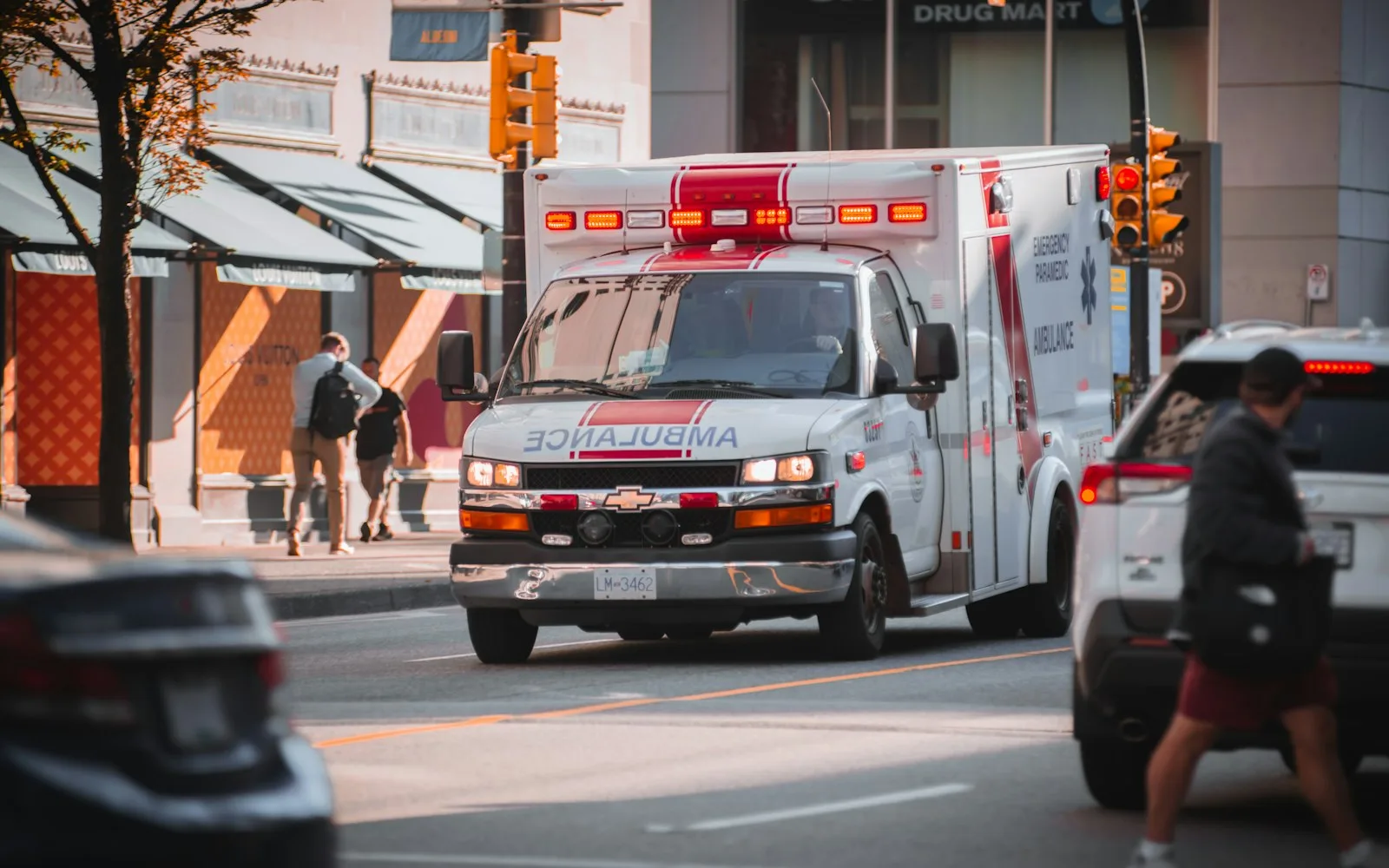 Sebuah ambulans melaju di jalan kota pada siang hari.