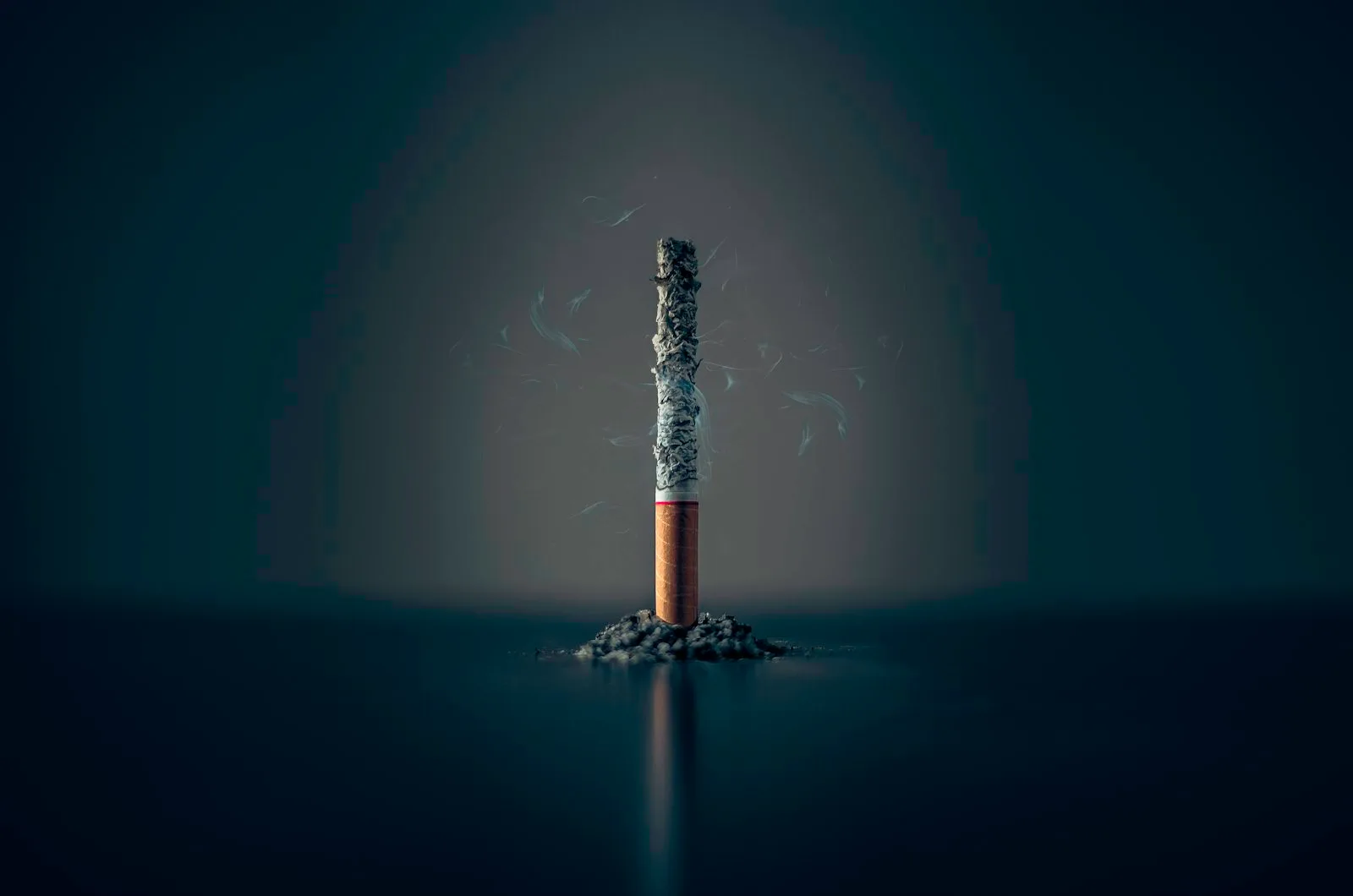 Sebatang rokok yang dipadamkan di atas latar gelap